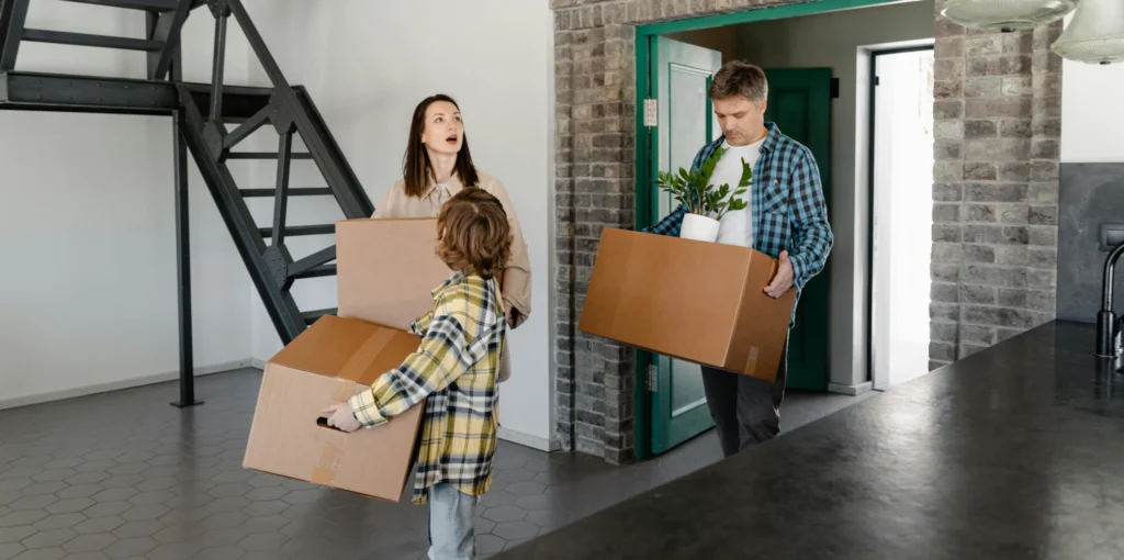 Junge Familie trägt gemeinsam Umzugskartons in ein neues Zuhause mit Umzugsunternehmen Hamburg