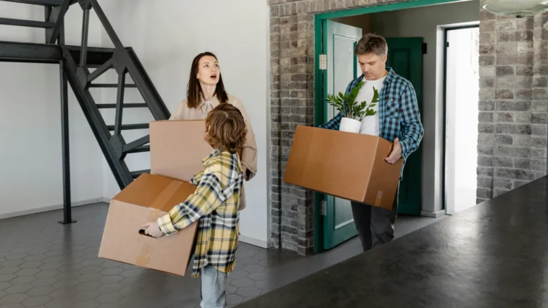 Junge Familie trägt gemeinsam Umzugskartons in ein neues Zuhause mit Umzugsunternehmen Hamburg